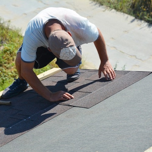 worker installing asphalt shingle roofing