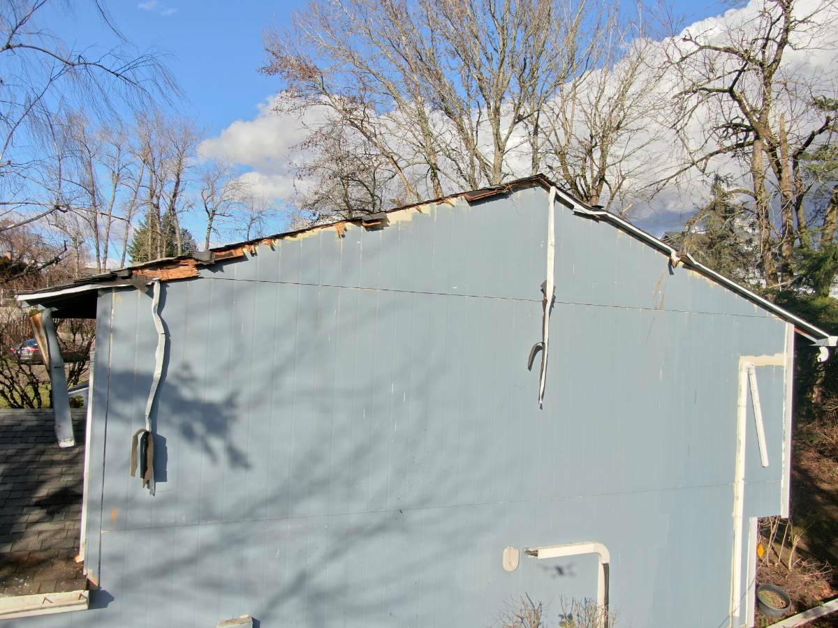Tree and storm damage visible along the roof edge and siding of the Gresham home before repairs